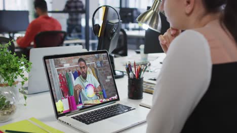 Caucasian-woman-having-a-video-call-with-male-colleague-on-laptop-at-office