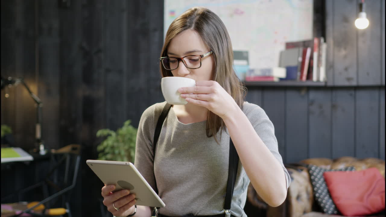 mujer usando tableta y bebiendo café