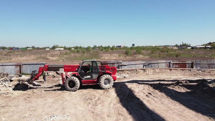 Construction site with red forklift and worker