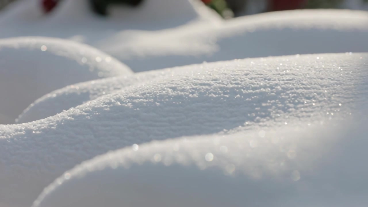 カメラの焦点が移動し、庭の丸い雪の山が現れ、きらめく雪の結晶が映し出される。