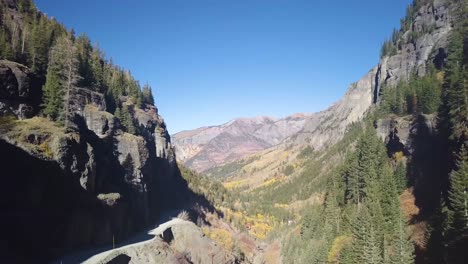 flying through a valley with aspen trees and a mountain road with dark shadows