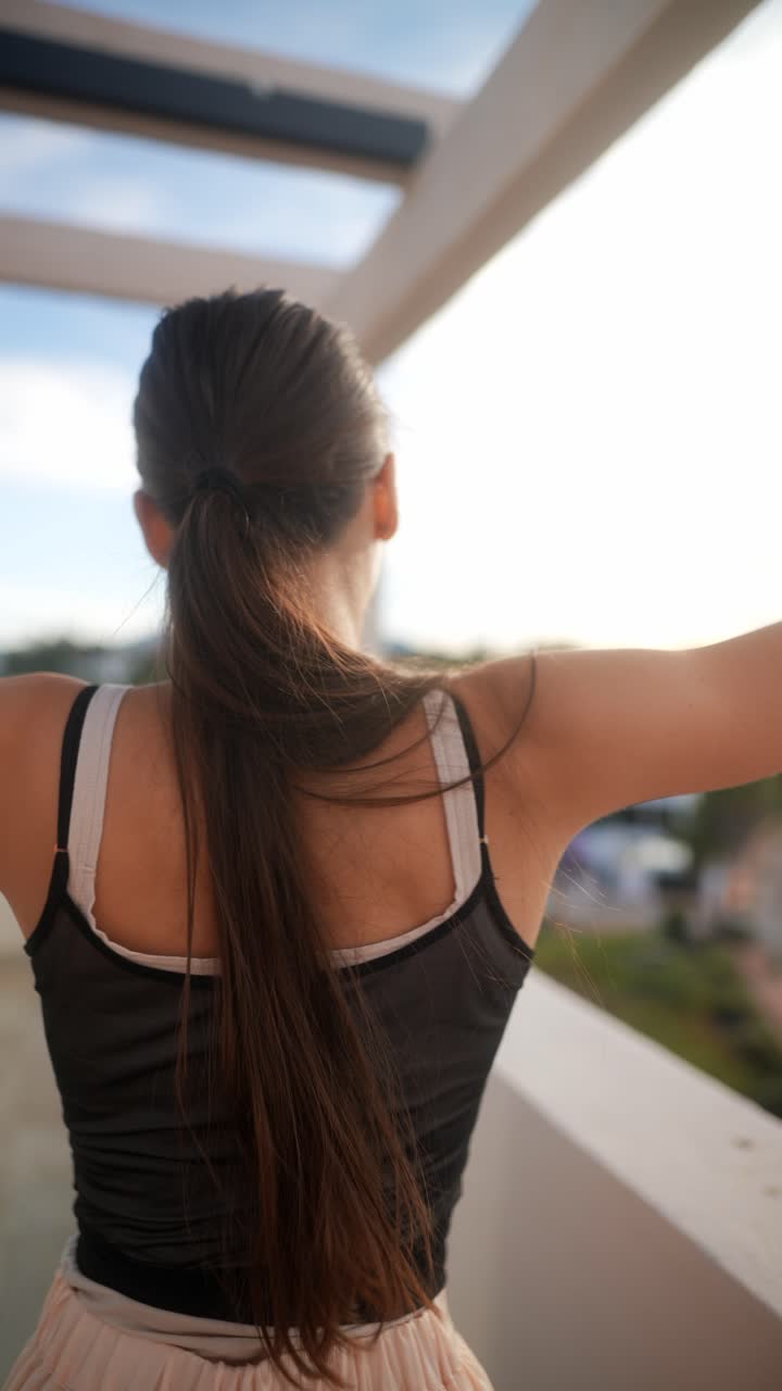 mujer estirándose en un balcón al atardecer