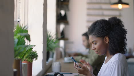 happy african american woman using smartphone in cafe browsing online messages enjoying sharing lifestyle on social media relaxing in coffee shop restaurant