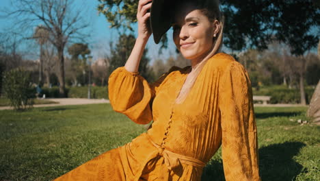 una joven elegante sentada en el césped al aire libre.