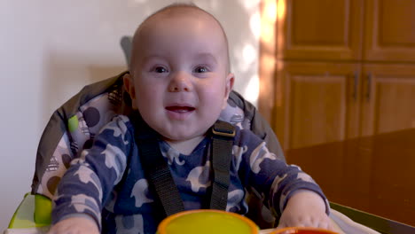 retrato de un niño feliz sonriendo y riendo en su silla alta