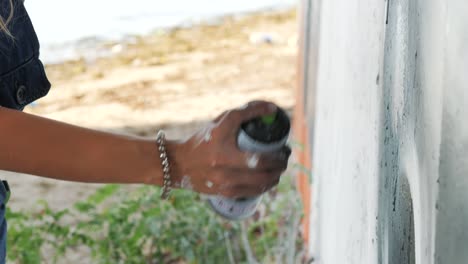graffiti artist painting on the street wall. female hand with aerosol spray bottle spraying with colorful paint, urban outdoors art concept. slow motion. close up view. 4k