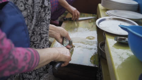 abalone being shucked to sell at a small food stall by seongsan ilchulbong peak, jeju island, south korea, medium dolly in slow motion.