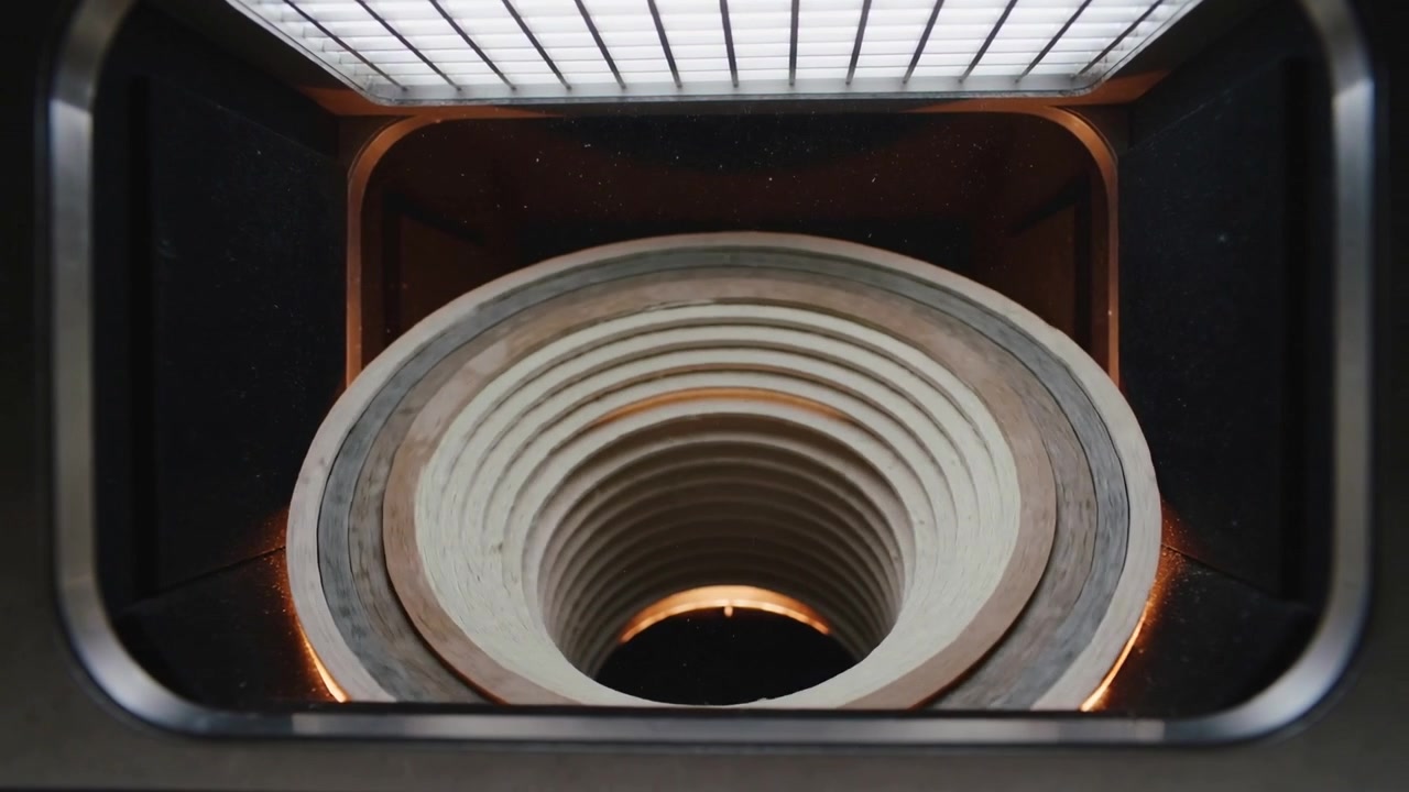 Forno che avvia il ciclo di cottura e riscalda un cilindro ceramico scanalato nella camera, mostrando un bagliore arancione