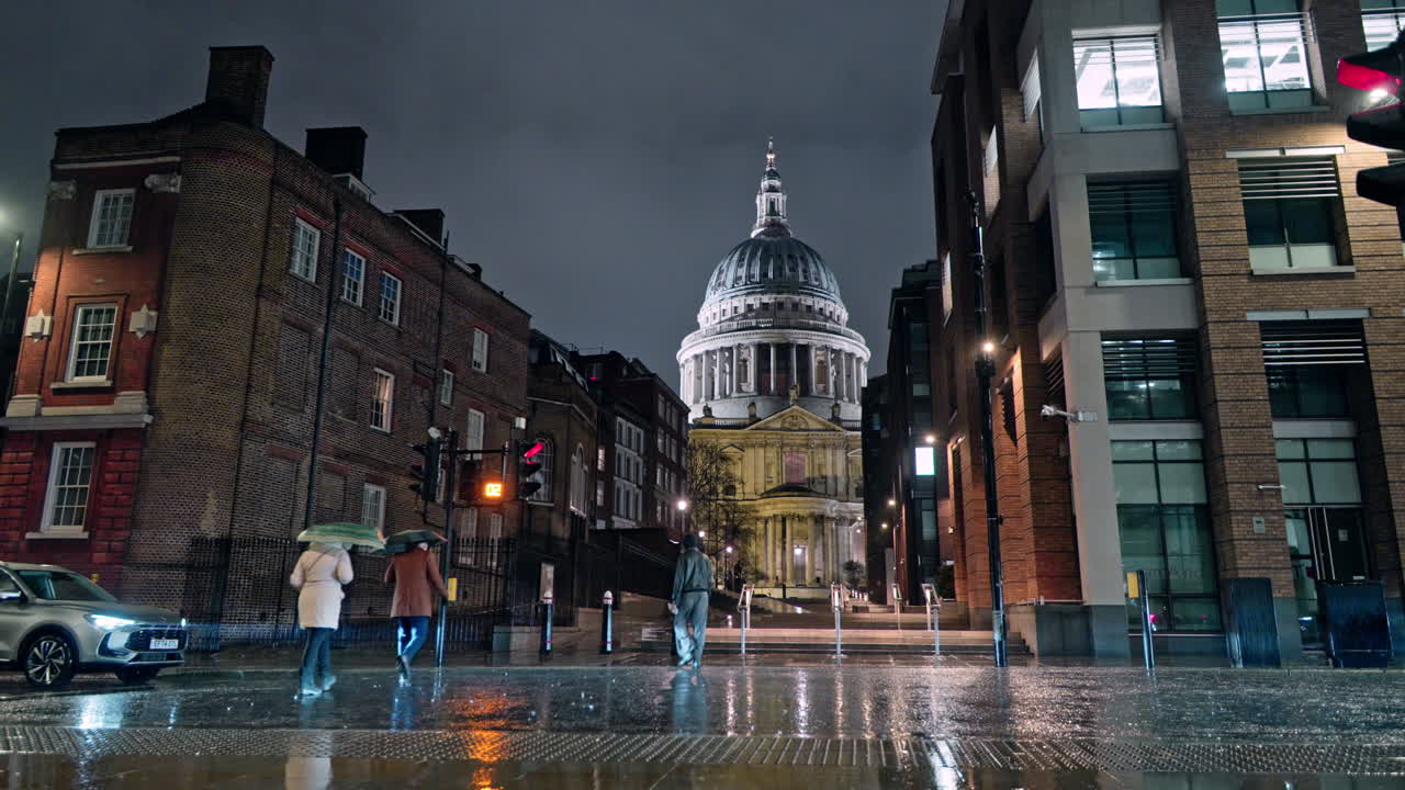 Rainy night view of St Paul's Cathedral in London, people and lights visible