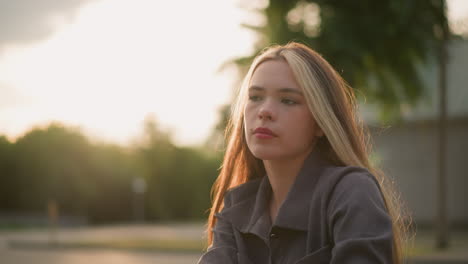 lady in grey shirt lost in thought, with sunlight creating a warm ambience in surrounding, background is blurred, with soft light reflecting around her