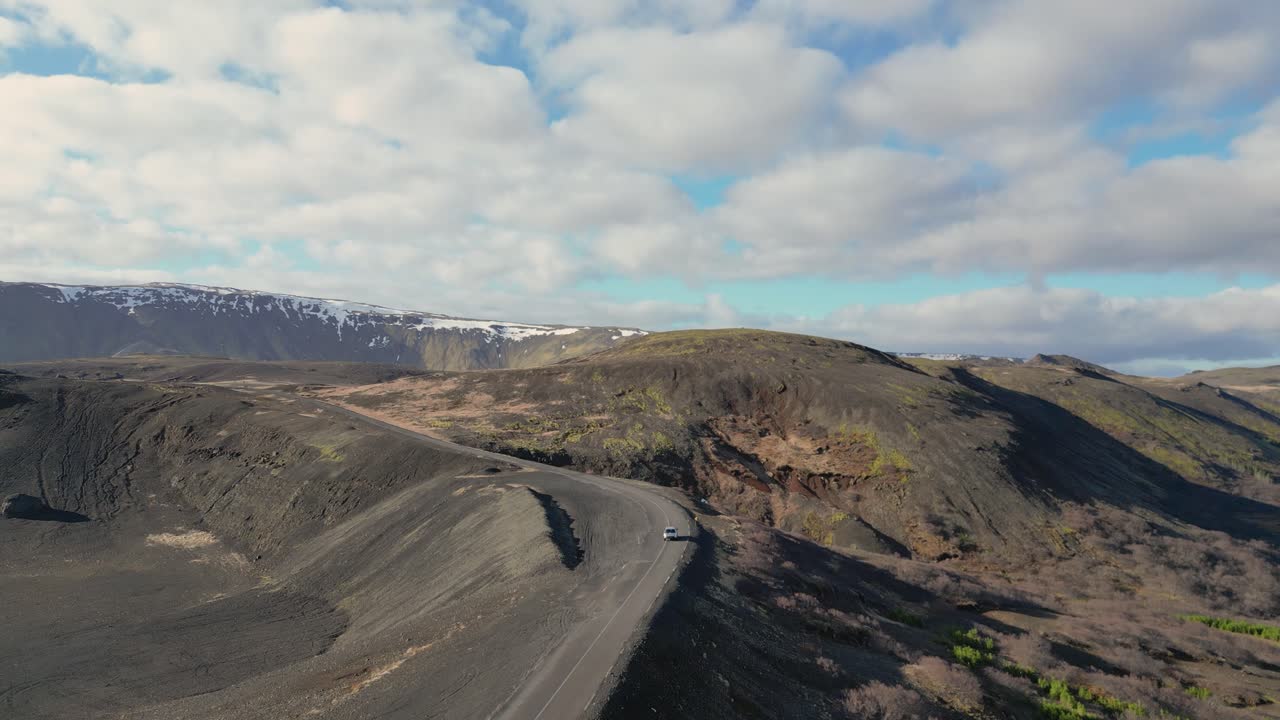 experimentar la belleza de los paisajes islandeses desde la perspectiva de un avión no tripulado, ver como un coche blanco navega por carreteras sinuosas a través de un paisaje volcánico, cruzando terrenos escarpados en un viaje estimulante