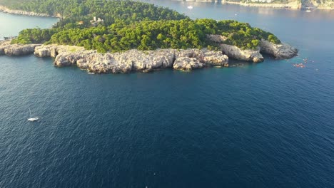 aerial view of a group of tourists on a kayak tour and boat passing by lokrum island near dubrovnik on the adriatic coastline of croatia