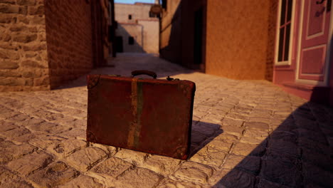 vintage suitcase abandoned in cobblestone alley