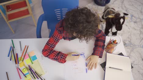 Little-boy-draws-a-picture-on-paper-with-colored-pencils.