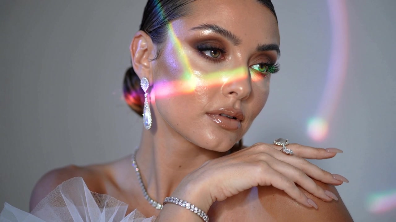 Modella che reagisce alla luce del prisma, si inclina, segue lo sguardo, mostrando gioielli su una balza di tulle in studio