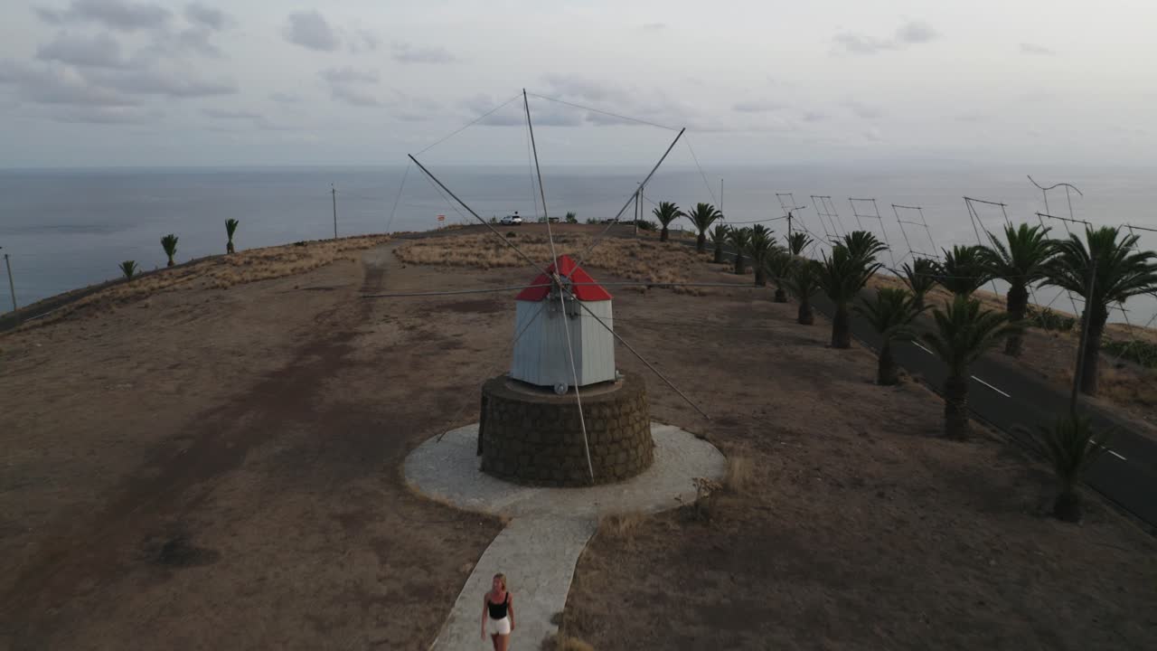 mujer viajera camina en los históricos molinos de viento de porto santo, antena
