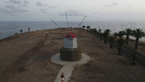 Mujer-Viajera-Camina-En-Los-Históricos-Molinos-De-Viento-De-Porto-Santo,-Antena