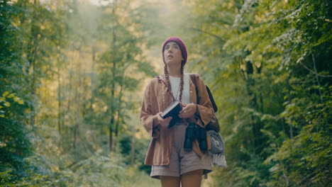 worried young woman with book exploring forest