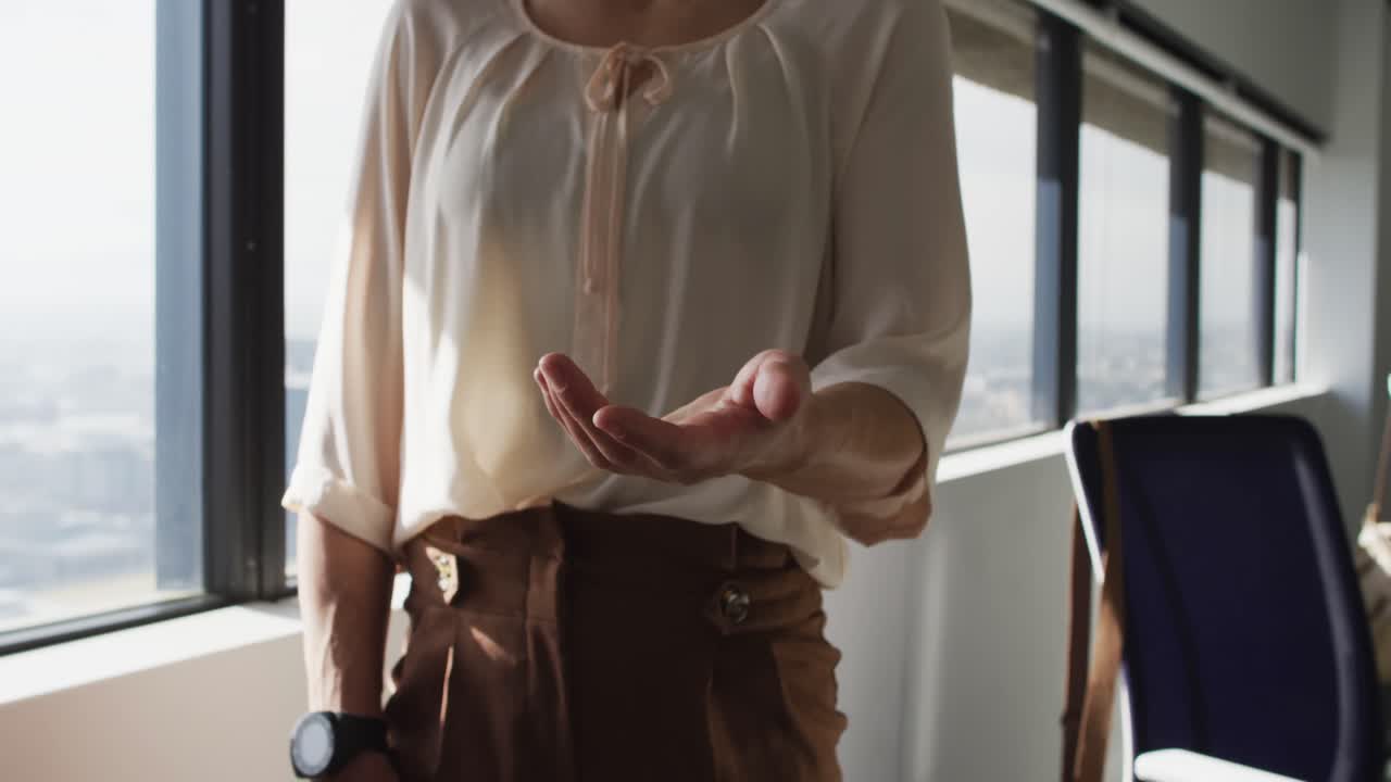 Midsection of caucasian businesswoman standing and gesturing at window