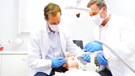 dentists examining a female patient with tools