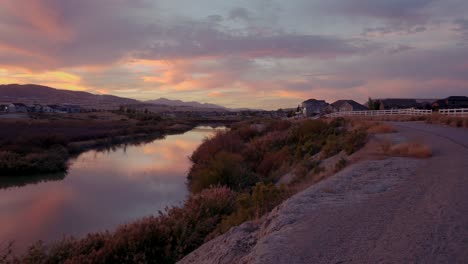 An-amazing-sunset-reflecting-off-a-calm-river-with-mountains-in-the-distance