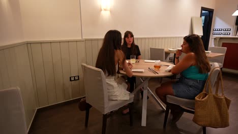 girl friends dining quietly at a table in a restaurant. static view