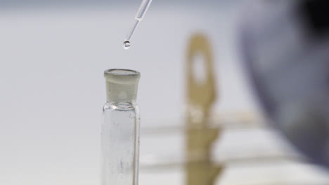 scientist using eye dropper to drip water into test tube