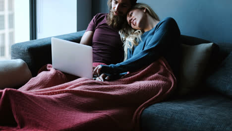 couple kissing while using laptop on sofa 4k