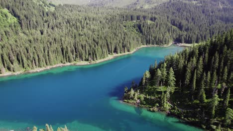 cinematic drone aerial over a beautiful alpine mountain lake surrounded by trees