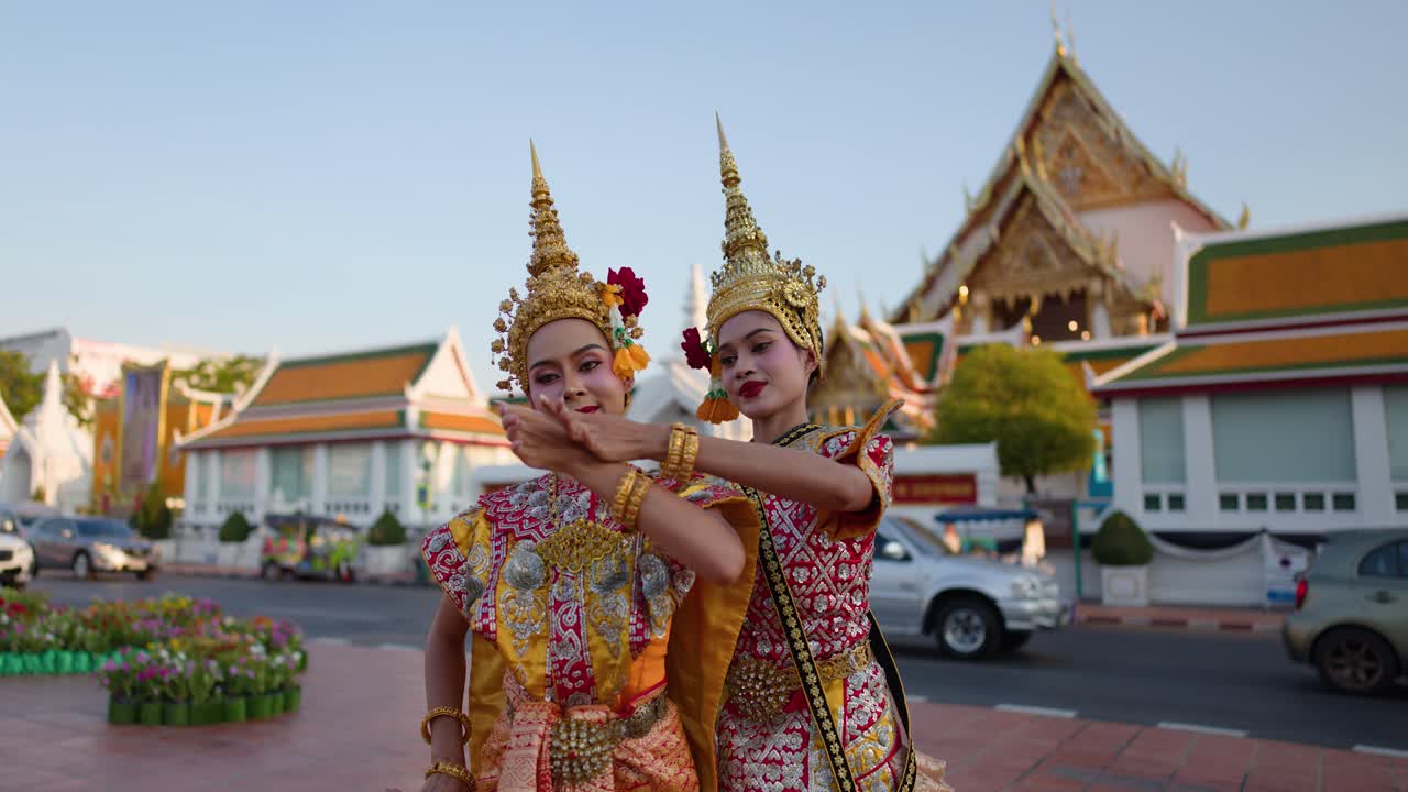 Due ballerini in sontuosi costumi dorati eseguono movimenti classici Khon fuori da un tempio storico di Bangkok