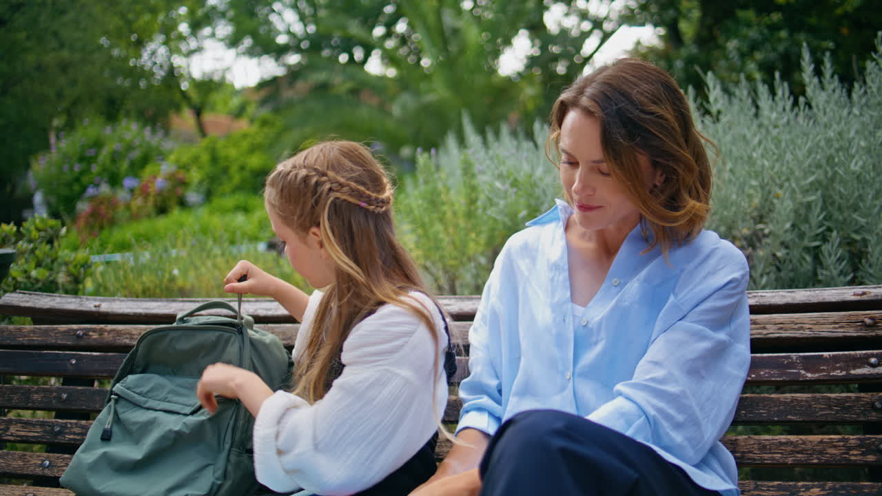 Closeup schoolgirl taking copybook giving woman at bright park. Doing homework