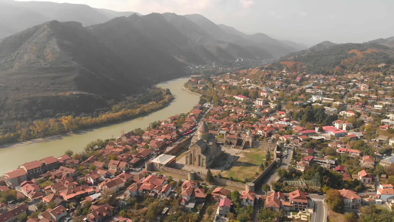 Video aereo che sorvola una chiesa nella città di Mtskheta in Georgia, con splendide montagne e un fiume