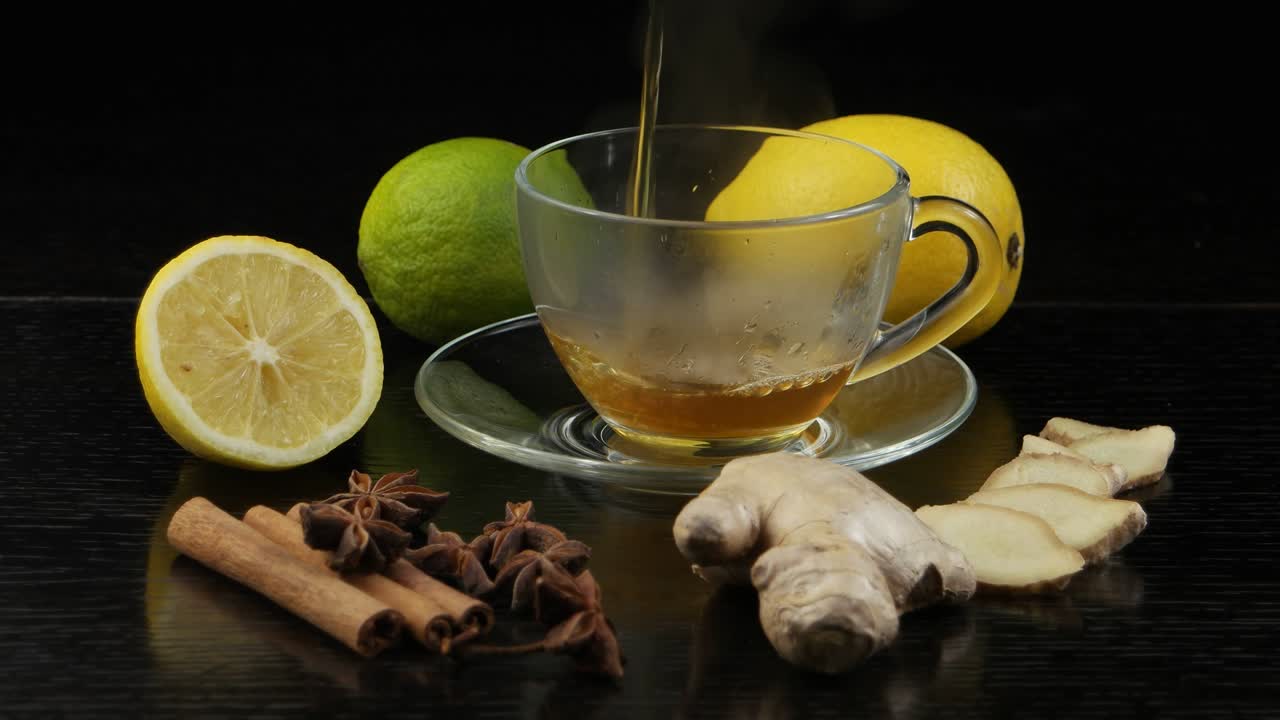 뜨거운 차는 유리 컵에 부어집니다. 검은 나무 테이블에 차를 위해 레몬, 라임 및 향신료