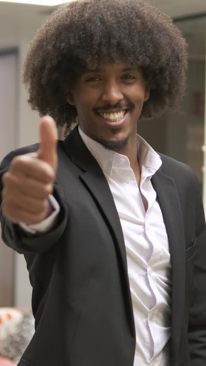 Happy confident creative businessman standing with thumbs up in office