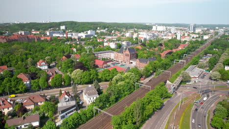 drone hacia atrás sobrevolando el distrito de wrzeszcz en gdansk con una vista de la universidad de tecnología de gdansk y los centros de transporte de la ciudad