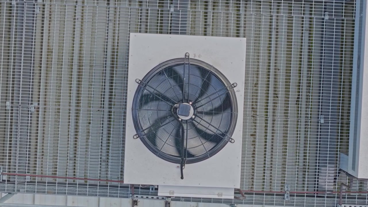 Luftoptagelser viser store industrielle køleventilatorer installeret på et moderne datacenter-tag. Klart dagslys fremhæver metalgitter, geometriske mønstre, avanceret ingeniørkunst og højteknologi.