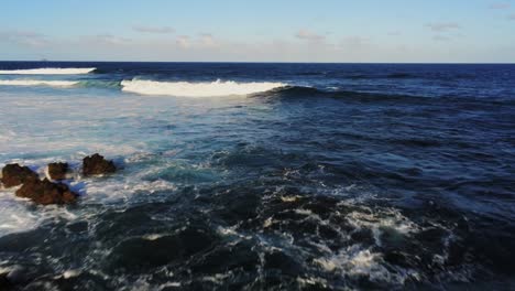 powerful ocean waves breaking near coastline of lanzarote, aerial fly backward view