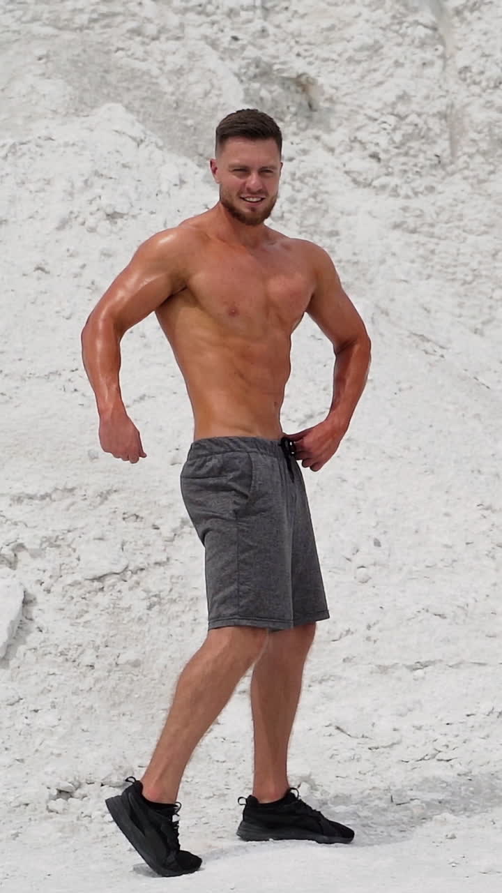 Sport man posing outdoor. Fit muscular young man with naked torso is posing on nature. Vertical video