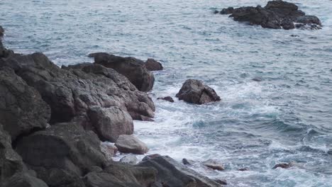 Entspannende-Blaue-Wellen,-Die-An-Der-Küste-Gegen-Große-Felsen-Prallen