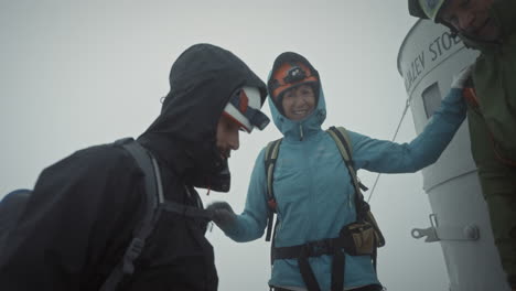 hikers congratulating themselves for the successful climb onto the peak of mountain triglav in front of aljaž tower