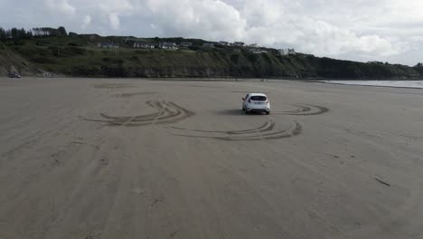 white car driving on a beach in ireland