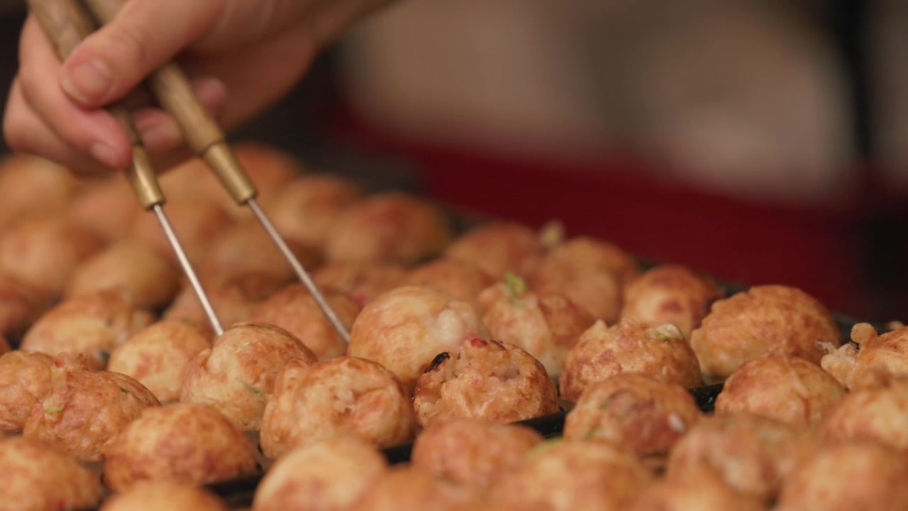 Takoyaki: palline di pastella che sfrigolano e vengono girate durante la preparazione - Primo piano.