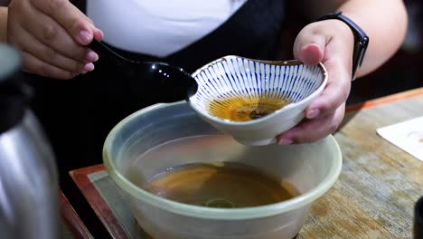 person transfers soup from small to large bowl