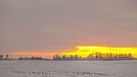 Campo-Congelado-De-Lapso-De-Tiempo-Cerca-De-La-Carretera,-Nubes-En-Movimiento-Cielo-Dorado-Rural-Riga,-Letonia