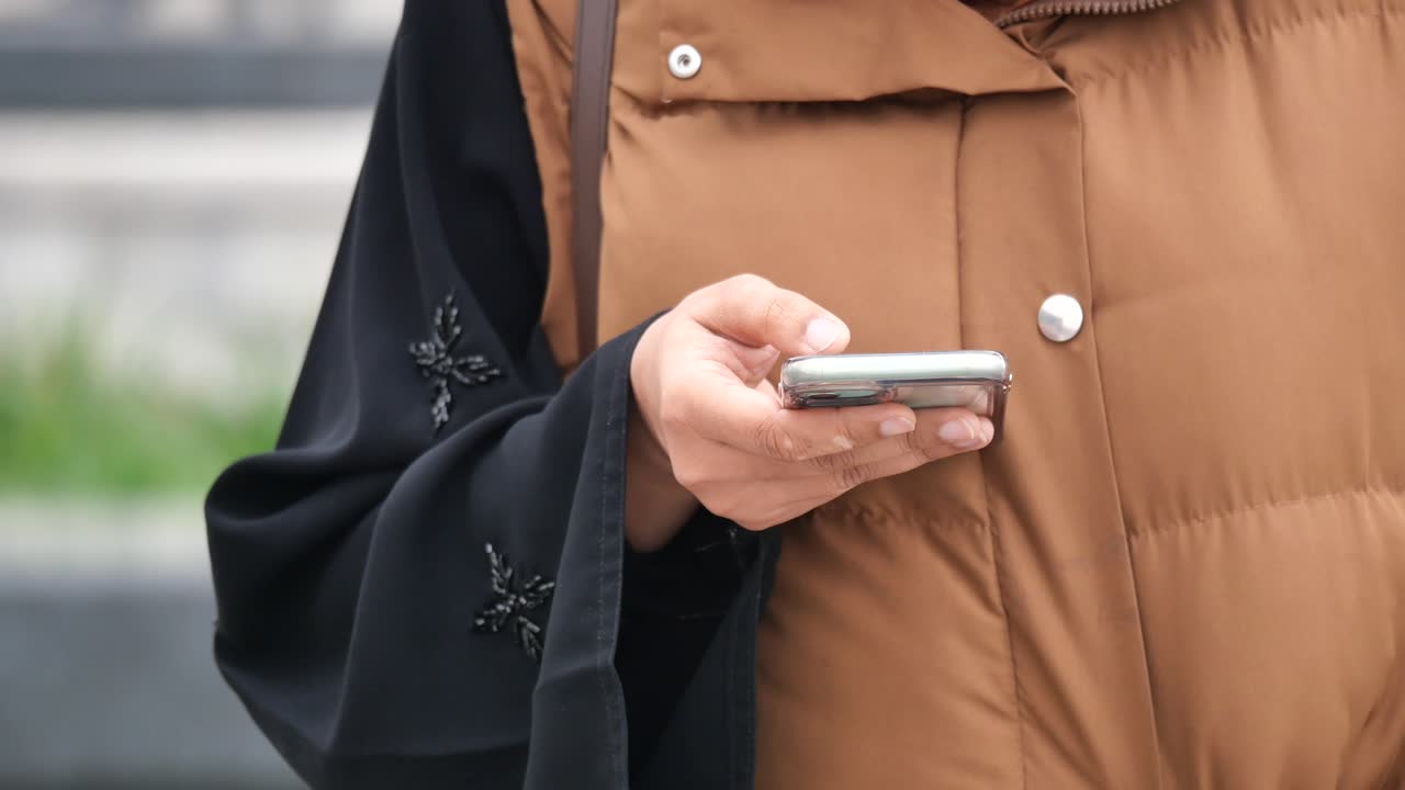 Woman using mobile phone while wearing abaya