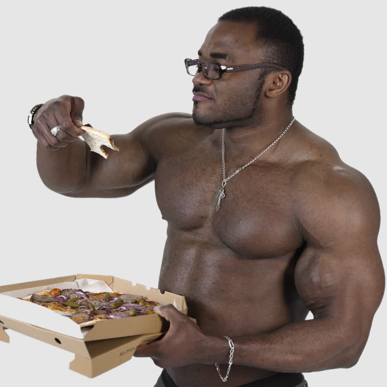 African american man eating pizza. Black muscular man enjoying delicious pizza from carton package. Sportsman eats unhealthy food isolated in studio. Slow motion