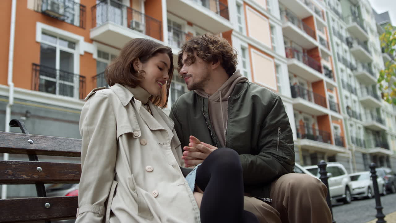 Coppia affiatata ad un appuntamento all'aperto. L'uomo accarezza la mano della donna per strada.