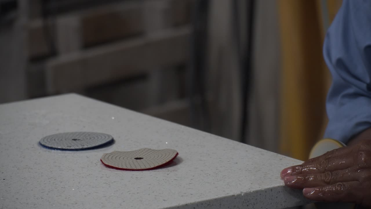 마스터 공예가 그라나이트 주방 카운터의 가장자리를 비벨하기 위해 도 은 샌더를 사용합니다.