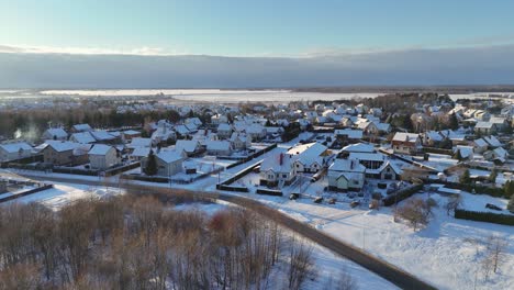 Vista-Aérea-De-Un-Pequeño-Pueblo-En-Medio-De-Un-Bosque-Durante-El-Invierno-Nevado