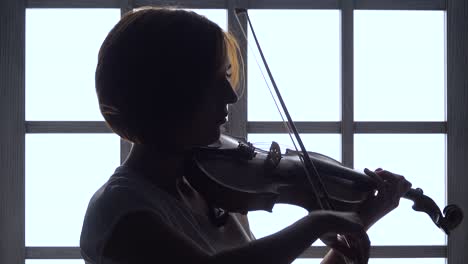 woman playing violin by window